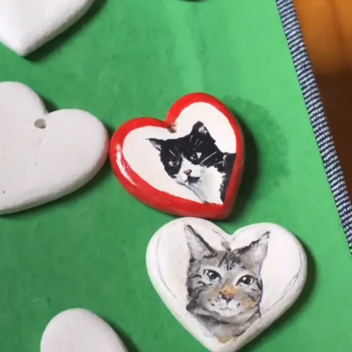 Charms de corazón con retratos de gatos, junto a corazones sin pintar
