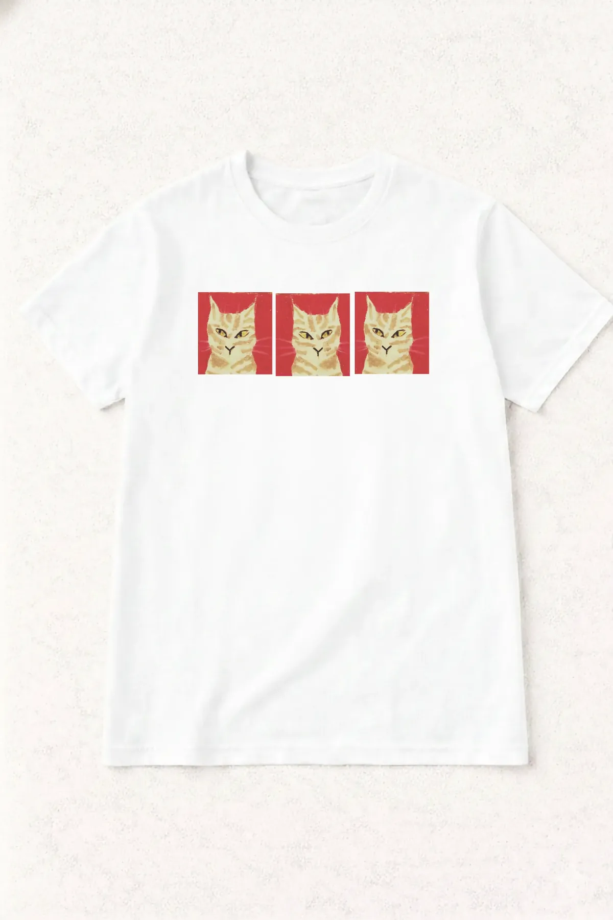 Polera blanca con tres retratos de un gato atigrado sobre fondo rojo